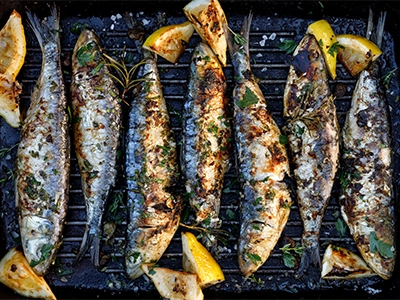 Grilled fishes in a herbal lemon marinade on a grill plate. 
